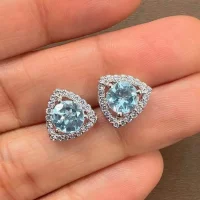 silver studs triangular shaped with 6mm round Blue Topaz and cubic zirconia displayed on hand
