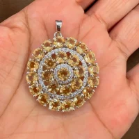 round shaped citrine and cubic zirconia studded silver pendant displayed on hand