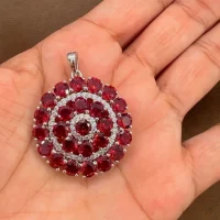 round shaped garnet and cubic zirconia studded silver pendant displayed on hand