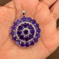 round shaped amethyst and cubic zirconia studded silver pendant displayed on hand