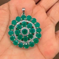 round shaped green onyx and cubic zirconia studded silver pendant displayed on hand