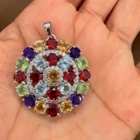 round shaped multi gemstone and cubic zirconia studded silver pendant displayed on hand