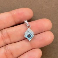 square shaped blue topaz with cubic zirconia silver pendant displayed on hand