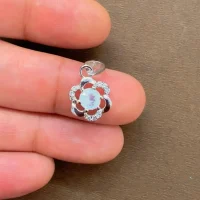 5mm round rainbow moonstone with cubic zirconia flower shaped silver pendant displayed on hand
