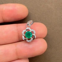 5mm round green onyx with cubic zirconia flower shaped silver pendant displayed on hand