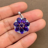 5x7 pear shaped amethyst with cubic zirconia flower shaped silver pendant displayed on hand