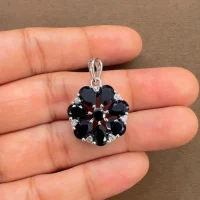 5x7 pear shaped black onyx with cubic zirconia flower shaped silver pendant displayed on hand