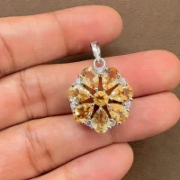 5x7 pear shaped citrine with cubic zirconia flower shaped silver pendant displayed on hand