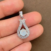 6mm round rainbow moonstone with cubic zirconia silver pendant displayed on hand