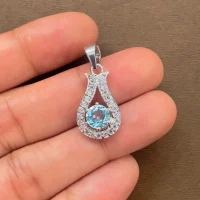 6mm round blue topaz with cubic zirconia silver pendant displayed on hand