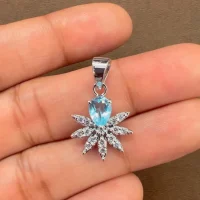 5x7 mm pear shaped blue topaz with cubic zirconia silver flower pendant displayed on hand