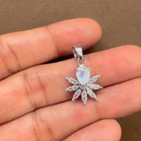 5x7 mm pear shaped rainbow moonstone with cubic zirconia silver flower pendant displayed on hand