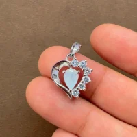 5x7 mm pear shaped rainbow moonstone with cubic zirconia silver heart shaped pendant displayed on hand