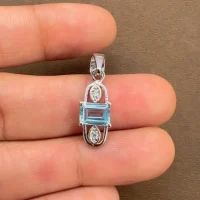 5x7mm octagon shaped blue topaz with cubic zirconia silver pendant displaying on hand