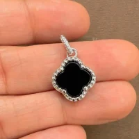 silver pendant clover shaped black onyx displayed on hand