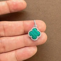 silver pendant clover shaped malachite displayed on hand