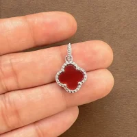 silver pendant clover shaped red onyx displayed on hand