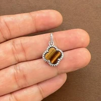 silver pendant clover shaped tiger's eye displayed on hand