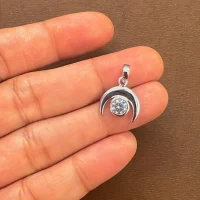 Moon shaped silver pendant with cubic zirconia displaying on hand