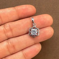 flower shaped silver pendant with cubic zirconia displayed on hand
