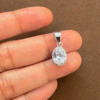 silver pendant with 7x9mm oval cubic zirconia in tar setting displayed on hand
