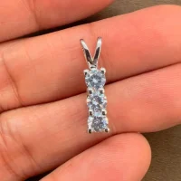 silver pendant with three piece 4mm round cubic zirconia displayed on hand