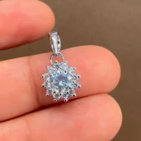 Silver pendant with 5mm round cubic zirconia in cluster gidha setting displayed on hand