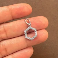 Hexagon shaped hollow silver pendant with cubic zirconia displaying on hand