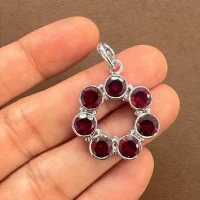 silver pendant round shaped with 6mm round garnet displayed on hand
