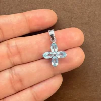 silver pendant flower shaped with 6x4mm oval blue topaz displayed on hand