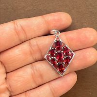 silver pendant rhombus shaped with different shape garnet displayed on hand