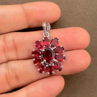 silver pendant flower shaped with garnet displayed on hand