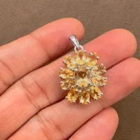 silver pendant flower shaped with citrine displayed on hand
