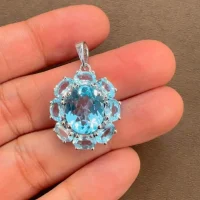 silver pendant with 10x12 mm and 6x4 mm oval blue topaz gemstone displayed on hand