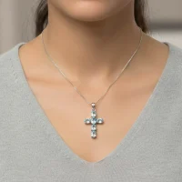 model wearing silver pendant cross design with 4x6mm oval blue topaz