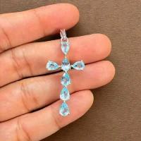 silver pendant cross design with 4x6mm pear blue topaz displayed on hand