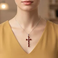 model wearing silver pendant cross design with 4x6mm pear garnet