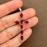 silver pendant cross design with 4x6mm pear garnet displayed on hand