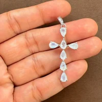 silver pendant cross design with 4x6mm pear rainbow moonstone displayed on hand
