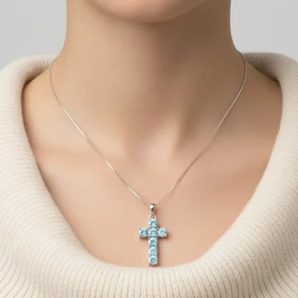 model wearing silver pendant cross design with 5mm round blue topaz
