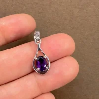 silver pendant with 5x7 mm oval shaped amethyst displayed on hand