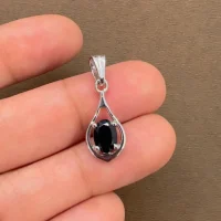 silver pendant with 5x7 mm oval shaped black onyx displayed on hand