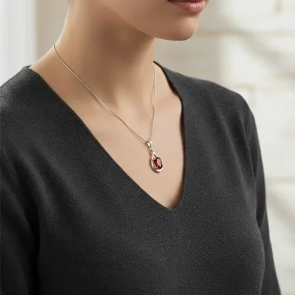 model wearing silver pendant with 5x7 mm oval shaped garnet