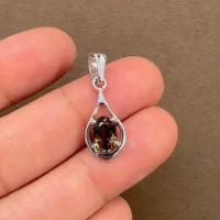 silver pendant with 5x7 mm oval shaped smoky quartz displayed on hand