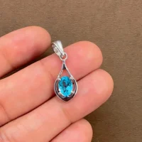 silver pendant with 5x7 mm oval shaped swiss blue topaz displayed on hand