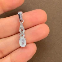 silver pendant with 5x7 mm oval rainbow moonstone displayed on hand