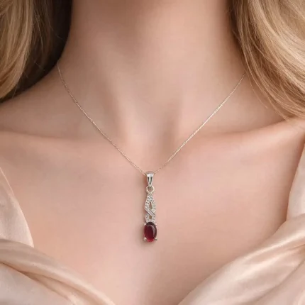 model wearing silver pendant with 5x7 mm oval garnet cabochon