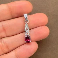 silver pendant with 5x7 mm oval garnet displayed on hand
