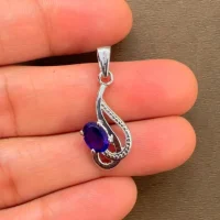 silver pendant with 5x7 mm oval amethyst displayed on hand