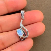 silver pendant with 5x7 mm oval rainbow moonstone displayed on hand